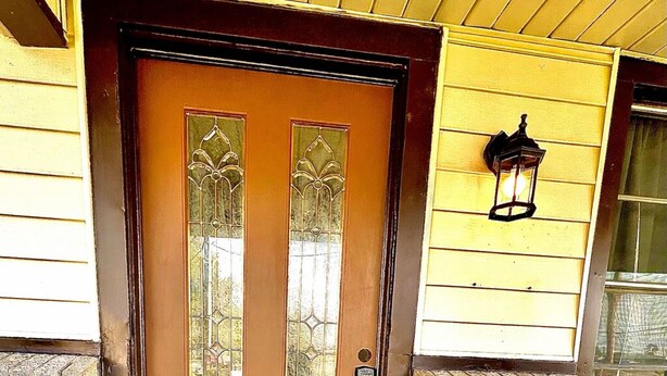 A brown wooden door with two vertical glass panels and a small doorbell.