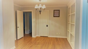 A hallway with wooden flooring, a chandelier, a closed door, and a wall with a motivational quote.