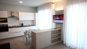 A modern kitchen with white cabinets, a gas stove, and a dining area with a table and chairs.
