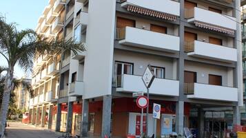 Un edificio residencial de varios pisos con balcones, un cartel de 'no estacionamiento' y una calle con motocicletas estacionadas.