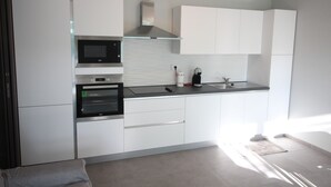 A modern kitchen with white cabinetry, a microwave, oven, and a glass range hood.