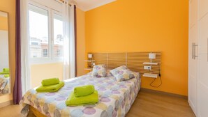 A bedroom with a bed, a nightstand, a lamp, and a window with curtains. - Casa Flors - 2 bedroom apartment with free wifi (Barcelona)