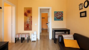 A living room with a sofa, a coffee table, a bench, and a small table with a lamp. There is a door leading to another room. - Casa Flors - 2 bedroom apartment with free wifi (Barcelona)