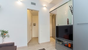 A modern living room with a flat-screen TV, a grey cabinet, and a brown sofa. - Gaudí Views- Suite with view on Hospital Sant Pau (UNESCO Heritage)  - FREE WIFI (Barcelona)