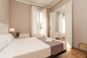A modern hotel room with a large bed, a bedside table, a lamp, and a potted plant.
