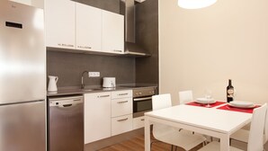 Une cuisine moderne dotée d’appareils électroménagers en acier inoxydable, une table à manger avec des chaises et un set de table rouge.