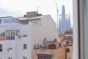 A residential building with multiple balconies, air conditioning units, and a view of a cathedral in the background.