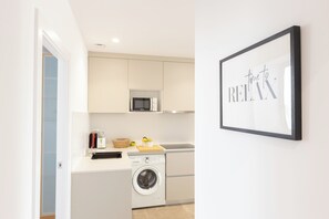 A modern kitchen with a microwave, washing machine, and a framed sign that says "time to RELAX".