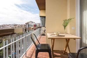 A balcony with a table, chairs, and a potted plant.
