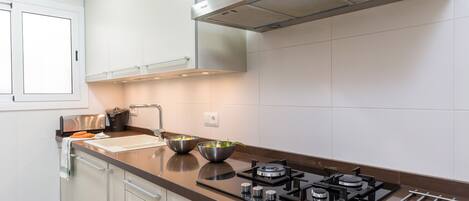 Cocina moderna con una campana extractora de acero inoxidable, una estufa a gas y dos tazones sobre la encimera.