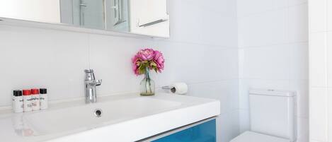 Un baño con un lavabo blanco, un espejo, un inodoro y un mueble azul.