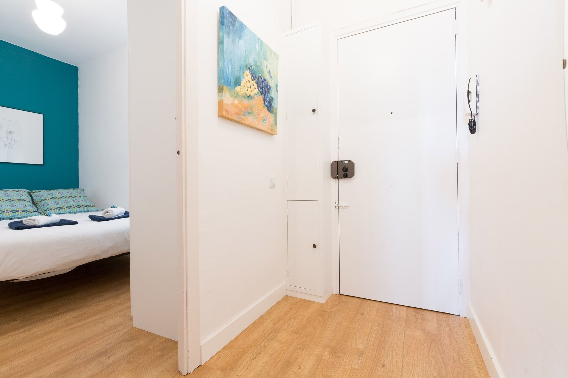 Un dormitorio con una cama, un cuadro y una puerta.