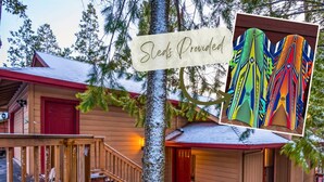 A cabin with a red door, wooden stairs, and a snow-covered tree. - Serenity in the Pines: Cozy Mountain Retreat (Twain Harte)