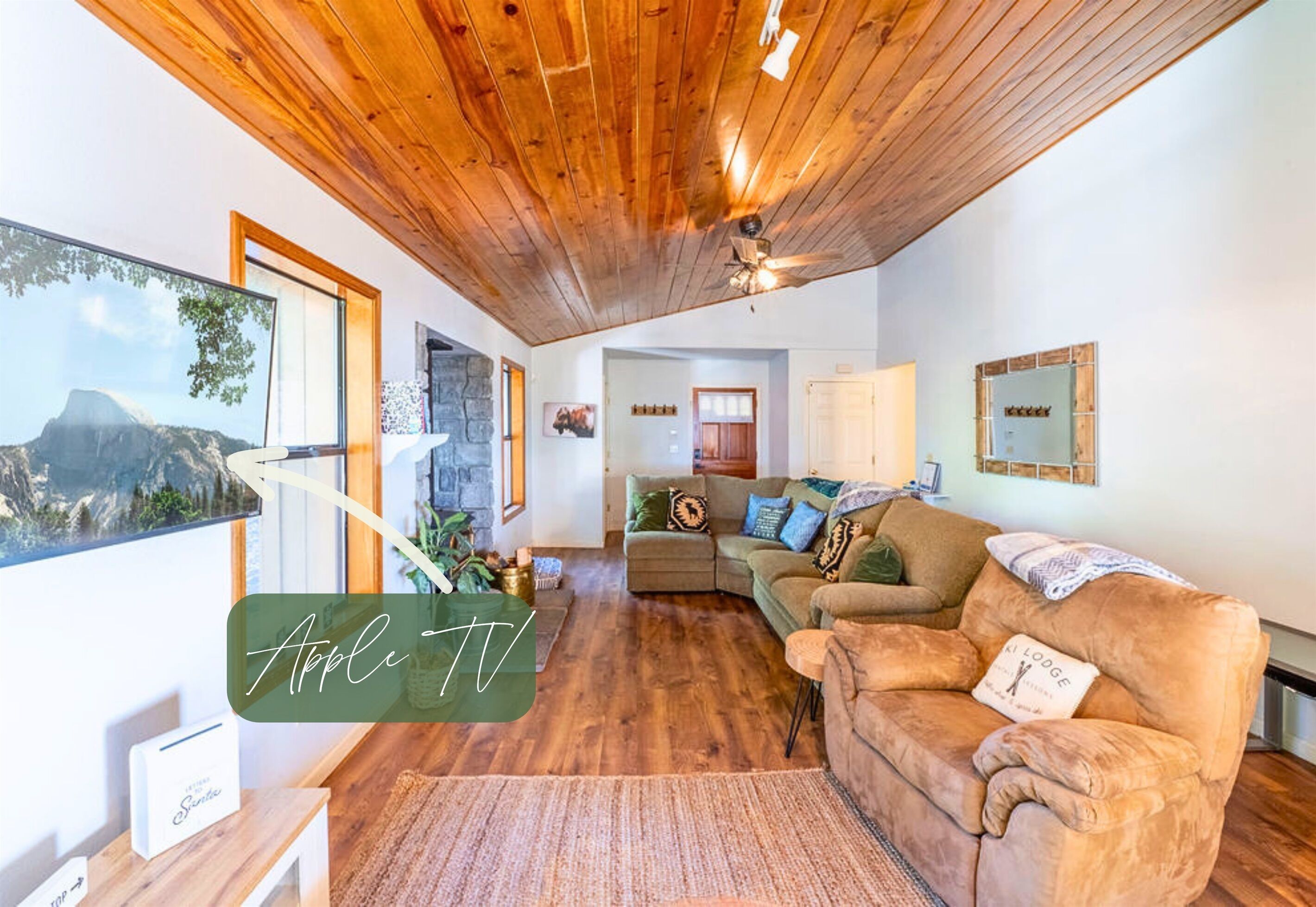 Una sala de estar acogedora con suelo de madera, un ventanal con vistas a la montaña, un sofá y un televisor.
