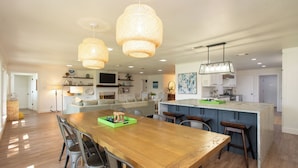 A spacious kitchen with a wooden dining table, bar stools, and pendant lighting. -  Beautiful Lake Front Home All Decked Out and Ready for Fun (Malakoff)