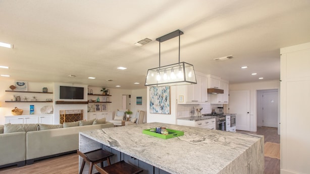 A modern kitchen with a large island, bar stools, and a hanging light fixture. -  Beautiful Lake Front Home All Decked Out and Ready for Fun (Malakoff)