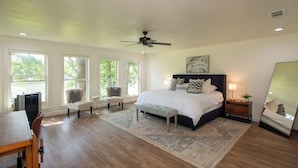 A bedroom with a bed, a desk, a chair, a ceiling fan, and large windows. -  Beautiful Lake Front Home All Decked Out and Ready for Fun (Malakoff)