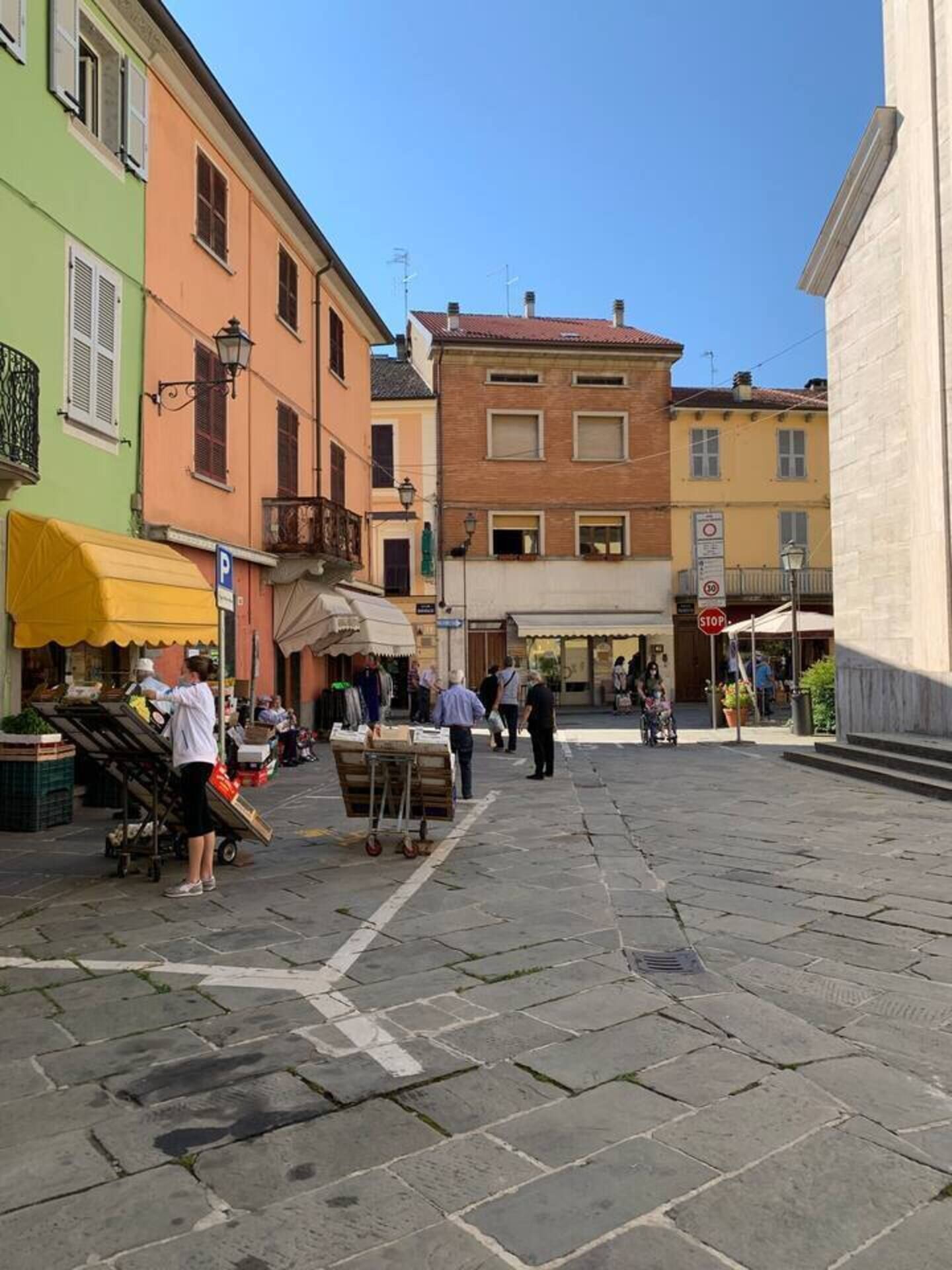 Une rue piétonne bordée de boutiques et abritant un marché couvert.