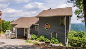 A two-story house with a porch and a decorative quilt on the wall. - Blue Ridge Blessing - Pet Friendly! Views, hot tub, great location on App Ski Mtn! (Blowing Rock)