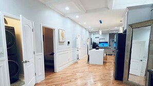 Un pasillo con suelo de madera, paredes blancas y puertas que dan a varias habitaciones.