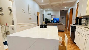 A modern kitchen with a central island, wooden flooring, white cabinetry, and a ceiling light fixture. - Modern Chicago Getaway • Sleeps 6 • Near Downtown (Chicago)