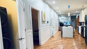 A hallway with wooden flooring, white doors, and a kitchen area with appliances. - Modern Chicago Getaway • Sleeps 6 • Near Downtown (Chicago)