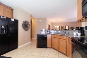 Fully equipped kitchen with central island, dishwasher, coffee maker, refrigerator, and microwave.