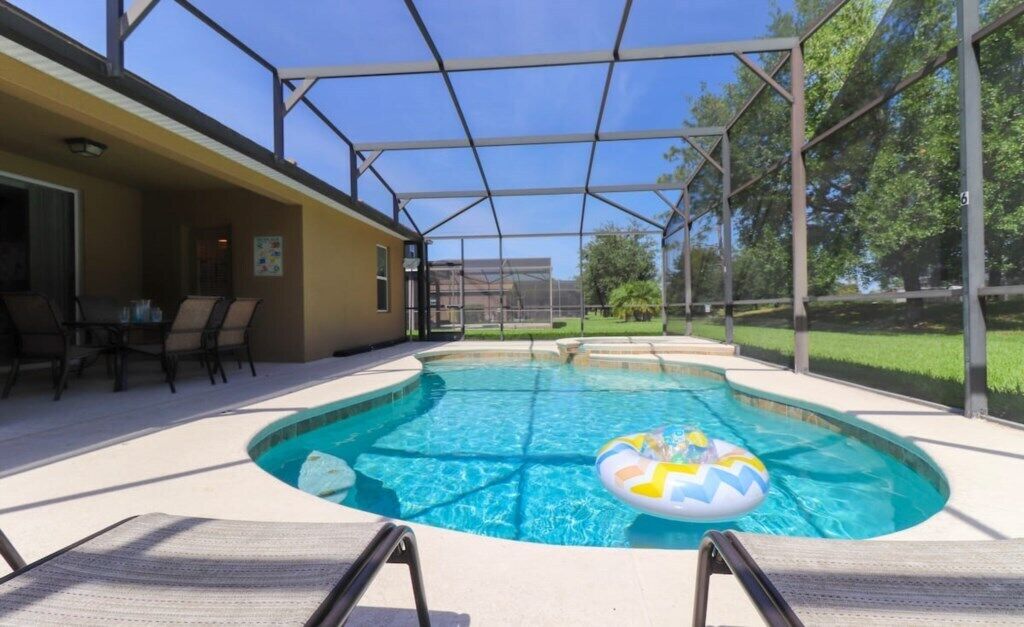 Ein Schwimmbecken mit überdachtem Bereich, Liegestühlen und einem Patio-Tisch.