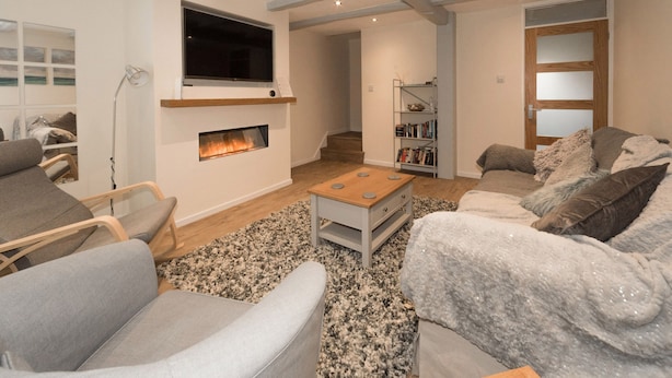 A modern living room with a fireplace, a flat-screen TV, and a bookshelf. - Seashells Cottage (Lytham St. Anne's)