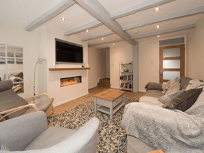 Een moderne woonkamer met een open haard, een flatscreen televisie en een boekenkast.