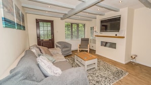 A living room with a grey sofa, a wooden coffee table, and a TV mounted on the wall. - Seashells Cottage (Lytham St. Anne's)