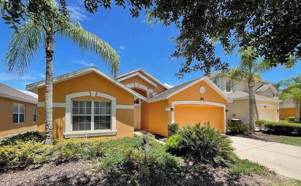 A residential house with a garage, a front yard with landscaping, and a clear blue sky.