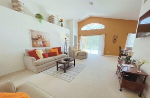 A spacious living room with a sofa, coffee table, and a desk with drawers.