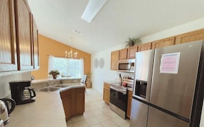 A modern kitchen with wooden cabinets, stainless steel appliances, a built-in oven, and a refrigerator.