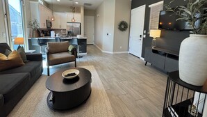 A modern living room with a sofa, coffee table, and a TV. - Desert Olive Retreat - Sleeps 4- 5 min fr Verrado Marketplace 30 min fr airport (Buckeye)