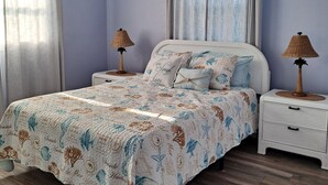 Een slaapkamer met een bed, twee nachtkastjes, een plafondventilator en twee lampen.
