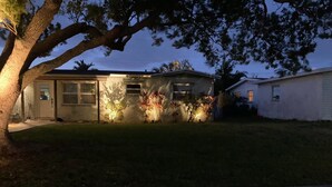 Een woonhuis met een garage, een verzorgd gazon en een boom die schaduw biedt.