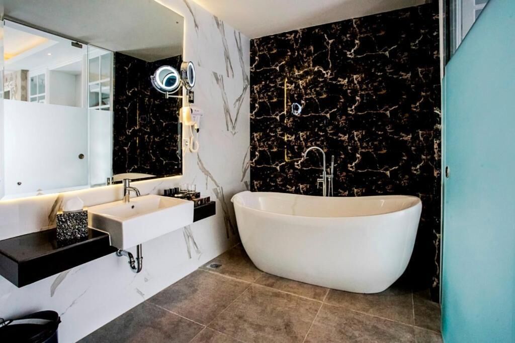 Une salle de bain moderne avec une baignoire sur pieds, un meuble-lavabo avec un miroir et des murs en marbre.