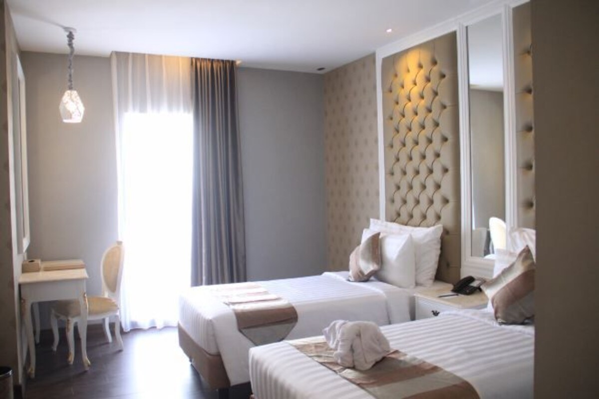 A hotel room with two beds, a desk, and a large mirror.