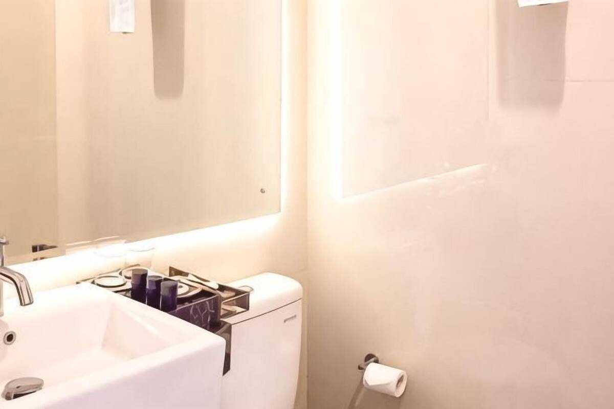 Un baño con lavamanos, espejo e inodoro.