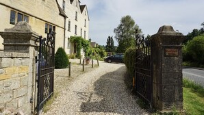 A gravel driveway leading to a gated entrance of a historic house with a sign reading "Grigshot House." - The Coach House and The Stable (Stroud)