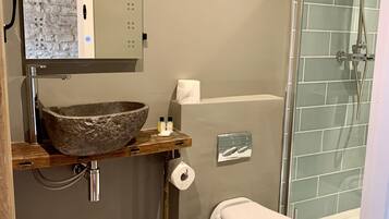 Een badkamer met een wastafel van steen, een toilet en een douchecabine met glazen wanden.