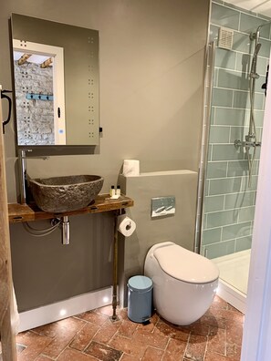 A bathroom with a stone sink, a toilet, and a glass shower enclosure. - The Coach House and The Stable (Stroud)