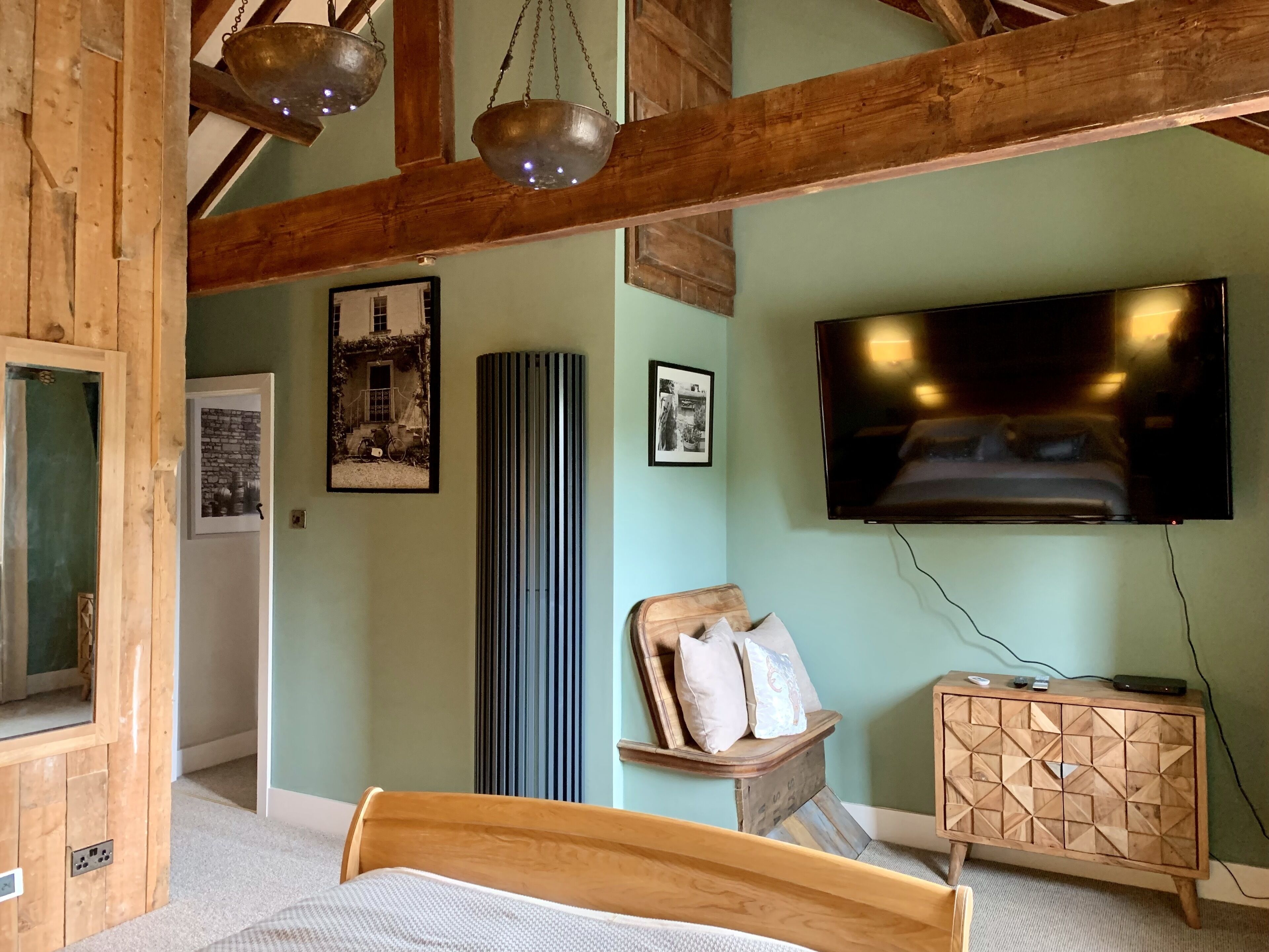 A bedroom with a wooden bed, a TV mounted on the wall, and a wooden cabinet.
