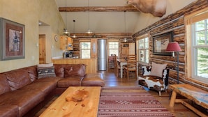 A rustic cabin interior with a living room, dining area, and kitchen.