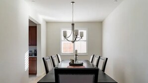 A dining room with a long table, chairs, and a chandelier.