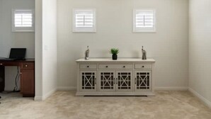 A room with a white wall, a white cabinet with glass doors, and a small plant on top.