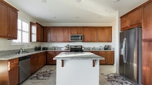 A modern kitchen with wooden cabinets, stainless steel appliances, and a central island.