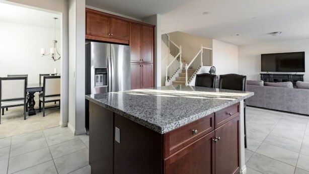 A modern kitchen with granite countertops, wooden cabinets, and a stainless steel refrigerator.