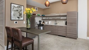 Una cocina moderna con comedor, que incluye una mesa, sillas, un florero y luminarias colgantes.